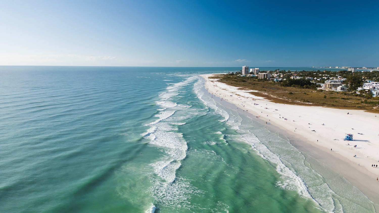 Drone Fly view over beach in Siesta Key, Florida. Beautiful Siesta Key beach on a sunny day. Turquoise transparent water and blue sea in Siesta Key beach.